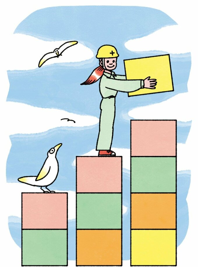 ヘルメットをかぶった女性が積み木を積み上げている