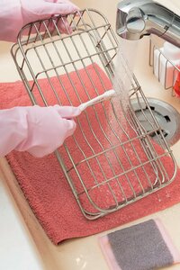 水きりカゴのヌメリを流水をかけながらこすり落とす