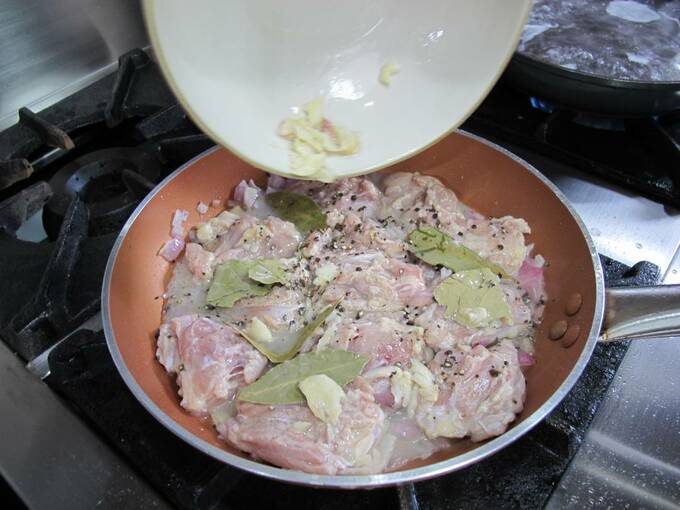 火を弱火にし、マリネの残り液、水、ブラウンシュガー、ローリエと黒コショウを加える