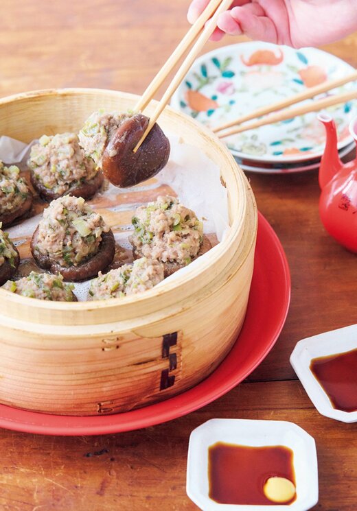 せいろから箸でシイタケシューマイを取り出している食卓の様子