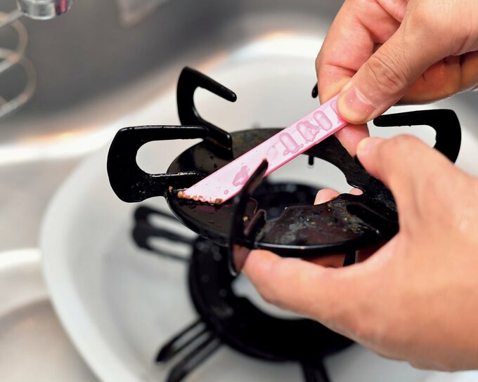 五徳のコゲつきをヘラで落とす