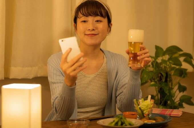 スマホとお酒を持つ女性