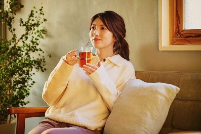 ソファでひとり晩酌をする女性