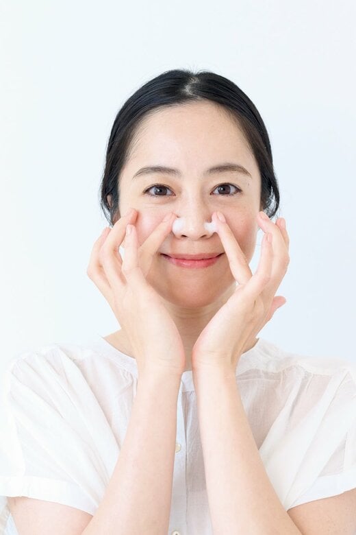 鼻の横にスキンケアクリームを塗る女性