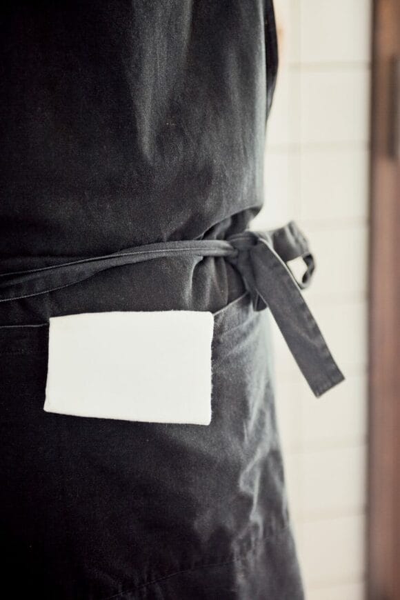 エプロンのポケットにコットンの手ふきを入れる