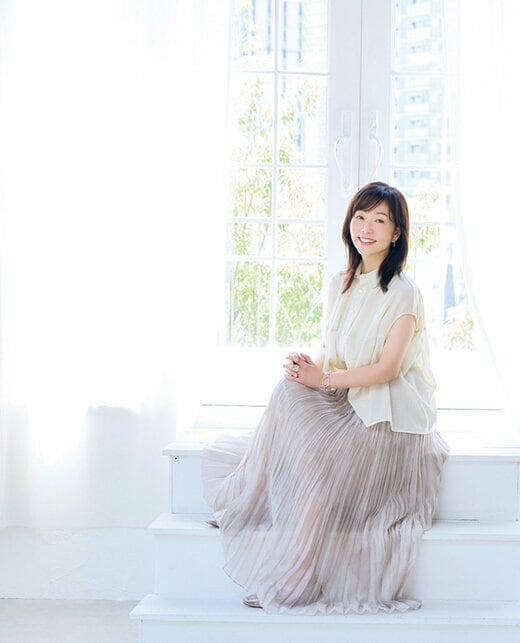 窓際に腰掛けほほ笑む女性