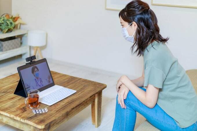 パソコンの前にマスクをつけた女性