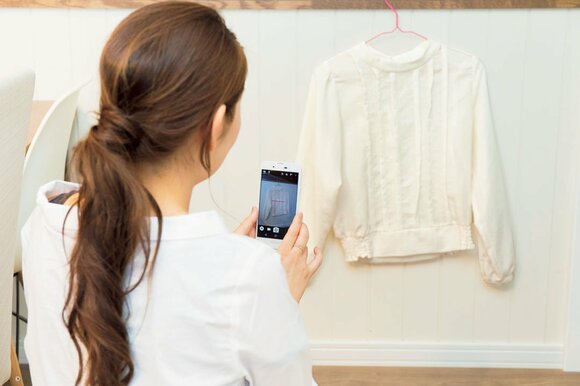 洋服をスマホで撮影する田中さん