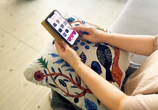 Nさんがスマホを操作し、アプリで服の管理をしている様子