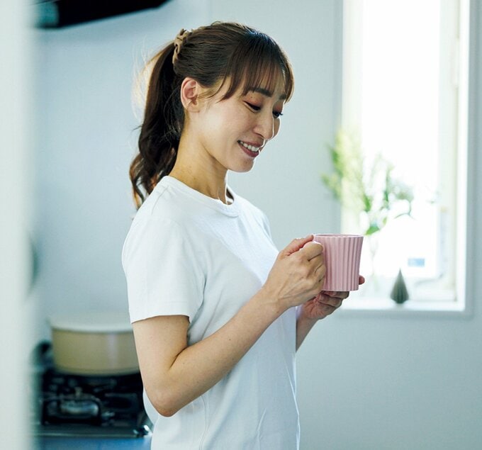 キッチンでピンクのマグカップを眺める女性