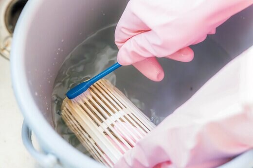 歯ブラシで排水口のぬめり取りをする手元