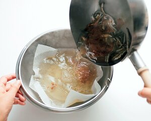 (5)カツオ節が鍋の底に沈むまでしばらくおいたら、ザルにペーパータオルを敷いてこす