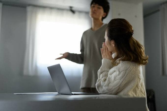 パソコンの前の女性と後ろに男性