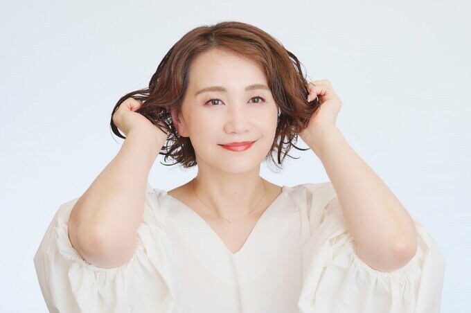 毛先にヘアミルクをもみ込んでいる女性