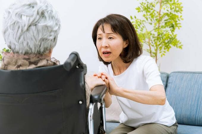 車椅子に座る女性と手をとる女性