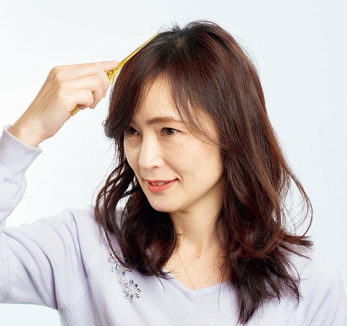 スプレーをつけたコームの柄でアホ毛を押さえる