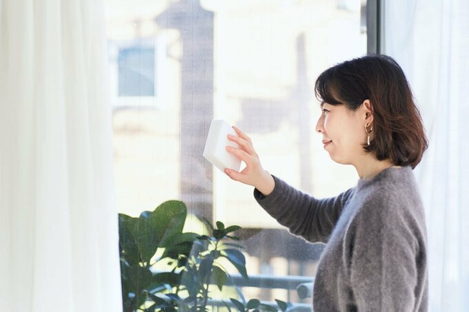 スポンジで窓をふいている女性