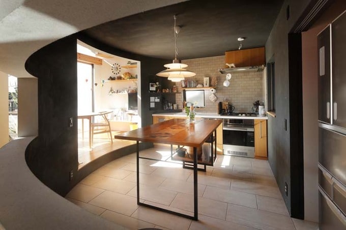 吹き抜けを貫く円筒形の壁とキッチン