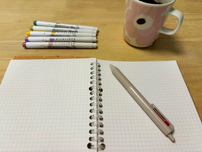 机の上に広げたﾉｰﾄとペン