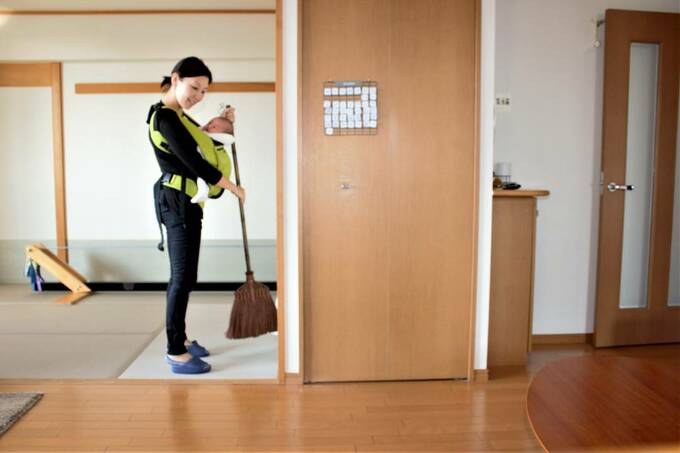 赤ちゃんを抱きながら掃除をする女性