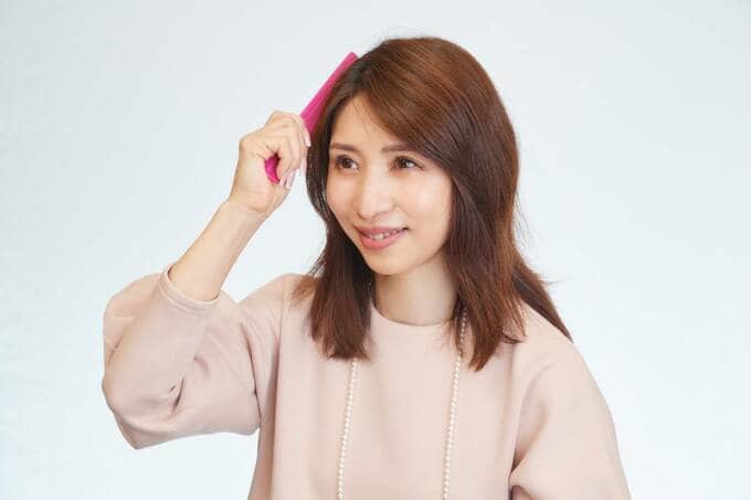 クシを根元に当てている女性