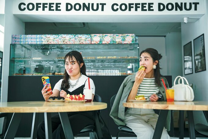 カフェで変顔をする女性と食事をしながらそれを見る女性