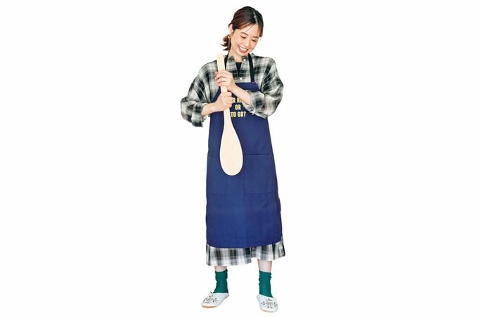 チェックワンピにエプロンを付けて、大きなしゃもじを持つ女性