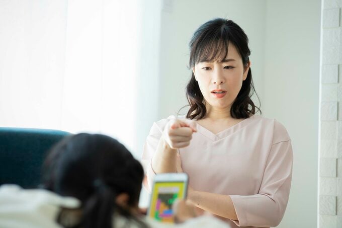 スマホゲームをする娘と叱る親