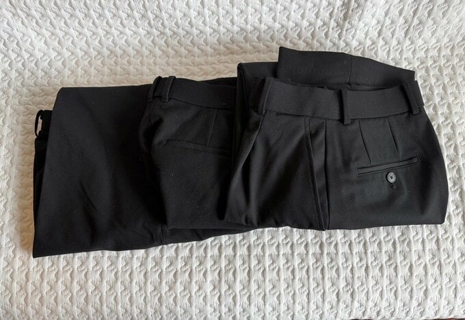 手放した黒のパンツ3本が並べて置いてある