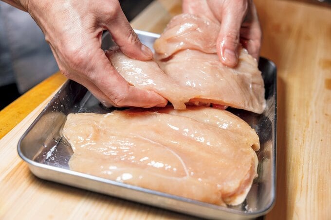 バットにのった鶏肉を手に取る様子