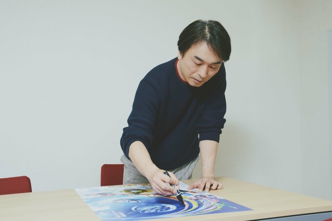 同じくポスターにサインをする関さん