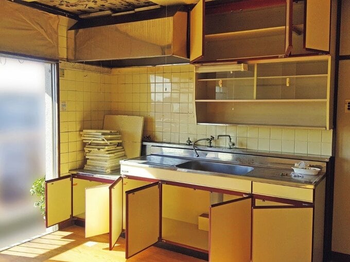 収納や壁のタイルが古びてあちこち汚れているキッチン