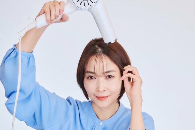 こめかみ部分の髪を乾かす女性
