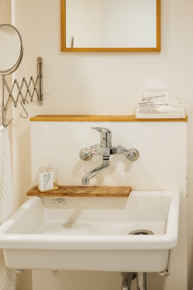 白と木目が基調の洗面所に置かれた、シンプルなペーパータオルやハンドソープ