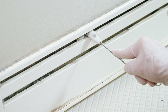 浴室ドアの溝をブラシで掃除する