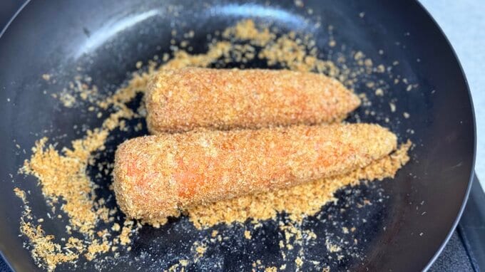 パン粉のをかぶったニンジンがフライパンに乗せられているところ