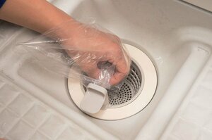 手にポリ袋をはめゴミをつまみ取る