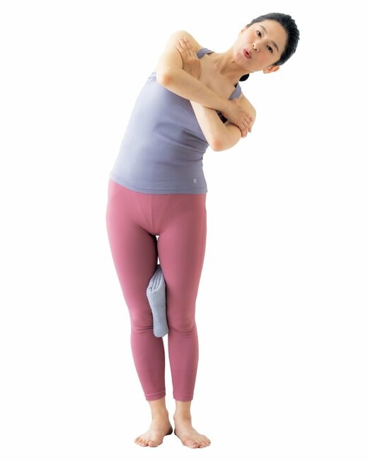 腕を胸前でクロスして上体を左に倒している女性