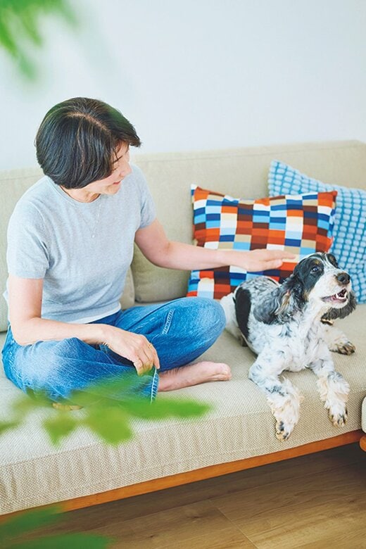 ソファに座り犬をなでる女性