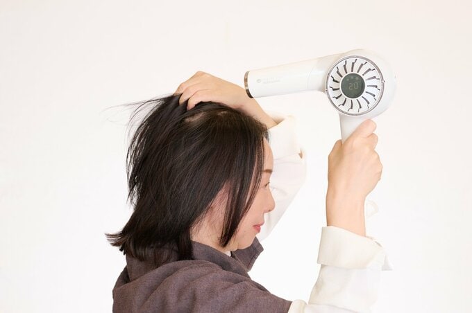 ドライヤーで髪を乾かす女性