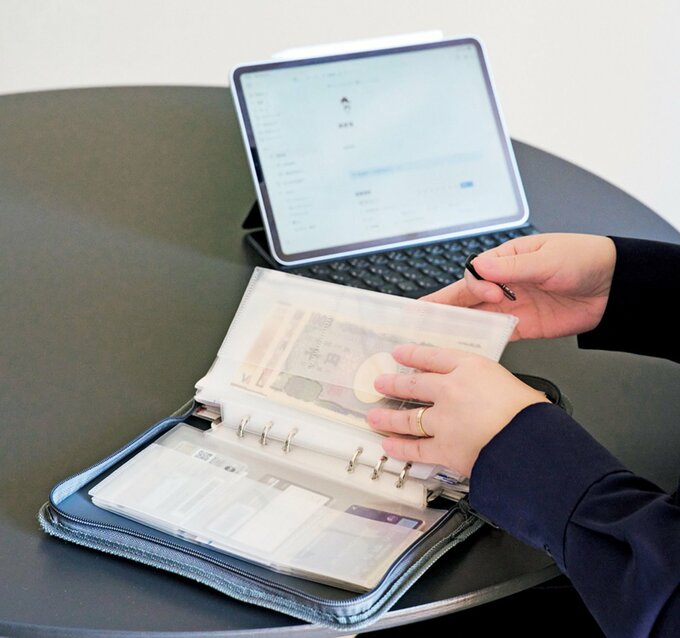 タブレットを見ながらお金を仕分けする手元