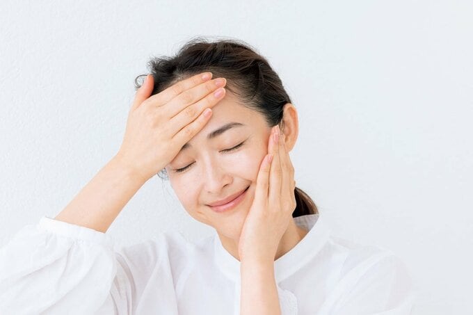 目を閉じて顔をおさえる女性