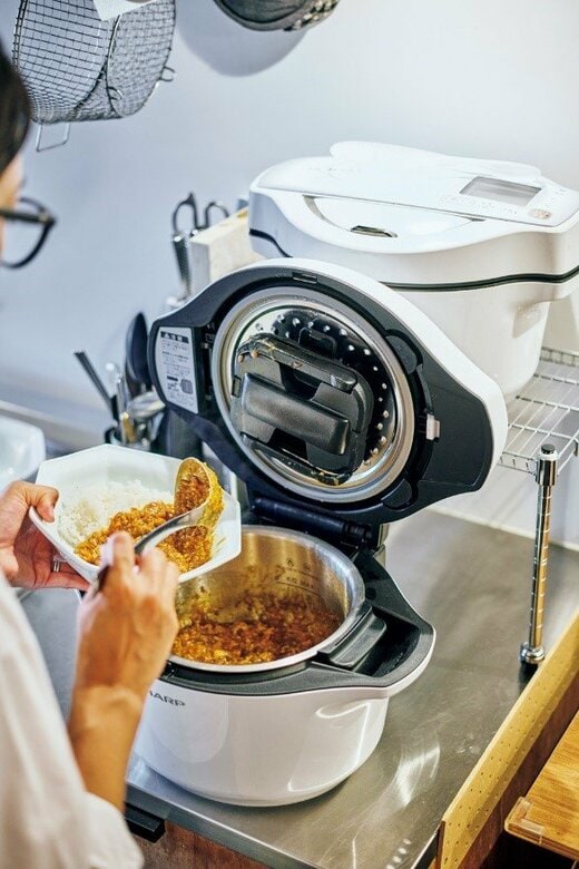 自動調理器で出来上がった料理を盛り付ける女性