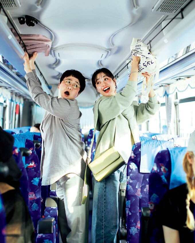 バスの棚に荷物を置く女性2人