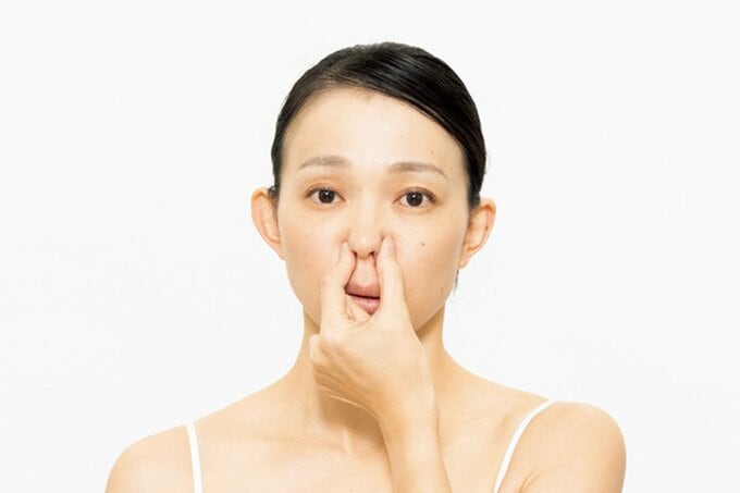 鼻をつまむ女性