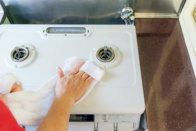 コンロの油汚れ掃除をする手元