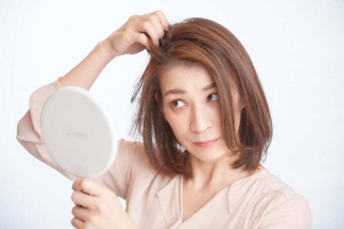鏡を見ながら髪を触る女性