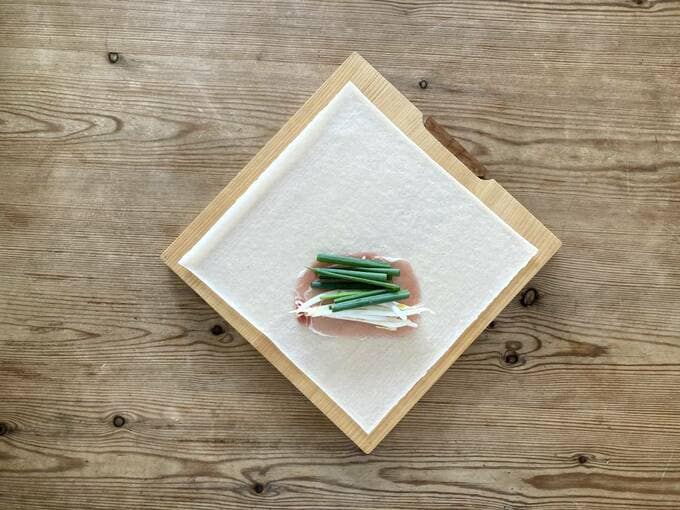 生春巻きの皮をひし型になるよう置き、手前に生ハム・モヤシ・小ネギをのせる