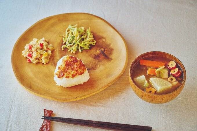 木の器に入ったおにぎりや野菜の和え物、みそ汁