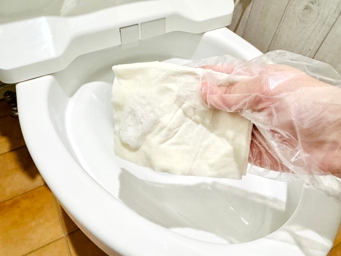 トイレットペーパーに洗剤をつけて拭き取る様子